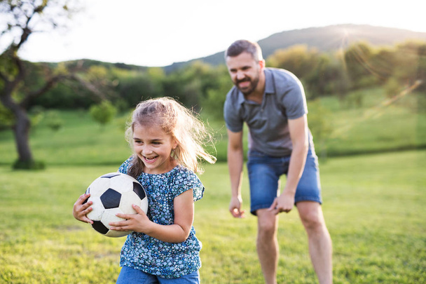 Father with a small daughter playing with a ball in spring nature. - Foto, imagen