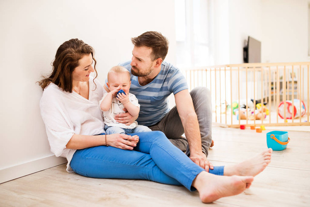 Young family with a baby boy at home, sitting on the floor. - Valokuva, kuva
