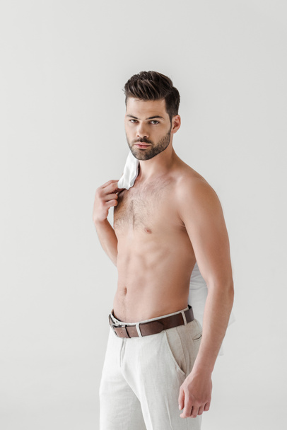 serious shirtless handsome male model posing with shirt on shoulder isolated on grey background - Photo, Image