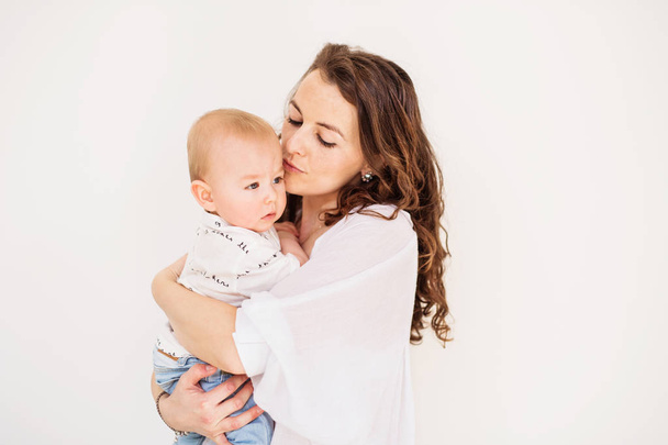 Portrait of a young mother kissing her baby son at home. Copy space. - Photo, image