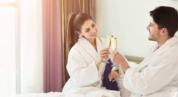 Ρομαντικό ζευγάρι πίνει σαμπάνια στο κρεβάτι - Φωτογραφία, εικόνα