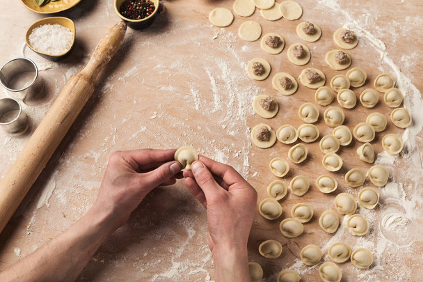 Chef-kok handen vormen kleine handgemaakte dumplings op keuken - Foto, afbeelding
