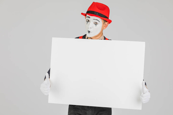 feliz artista MIME sosteniendo una pizarra blanca en blanco, sobre un fondo blanco - Foto, imagen