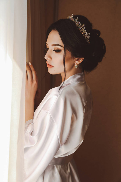 fashion photo of beautiful bride with dark hair preparing her makeup and hairstyle  in her wedding morning - Photo, Image