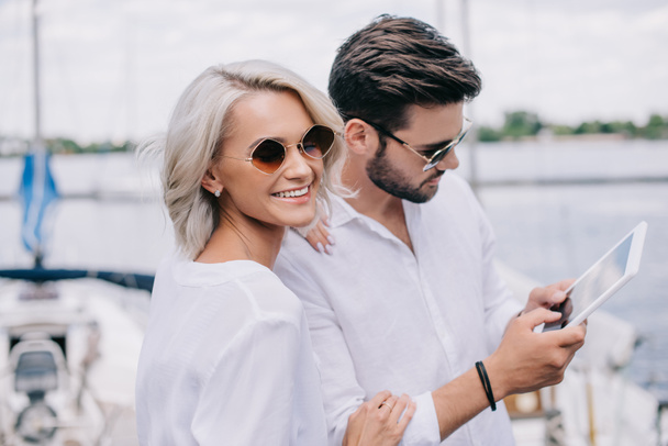 beau sourire jeune couple dans des lunettes de soleil en utilisant tablette numérique sur yacht
 - Photo, image