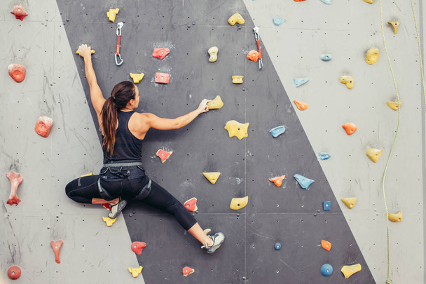 Young climber woman climbing on practical rock in climbing center, bouldering - Foto, Imagem