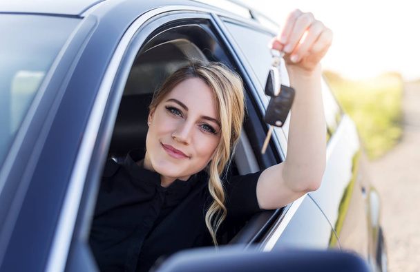 Una mujer atractiva en un coche tiene una llave en la mano
. - Foto, imagen