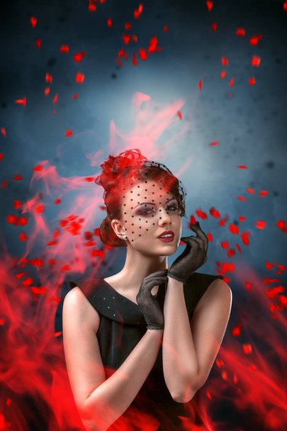 Abstract fashion portrait of young woman with flame and smoke over dark background - Fotó, kép