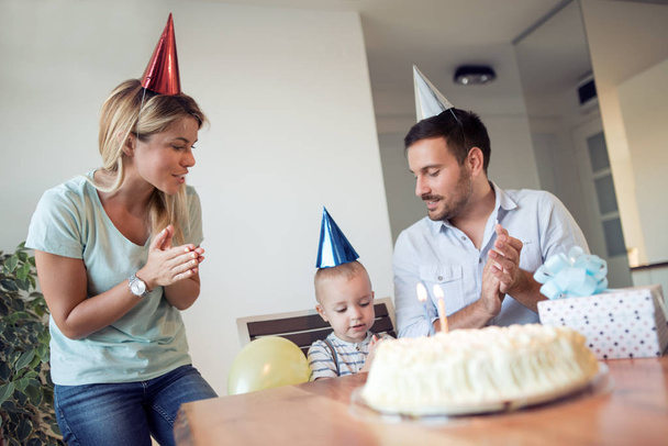 誕生日。パーティーでの誕生日ケーキのろうそくを吹く少年. - 写真・画像