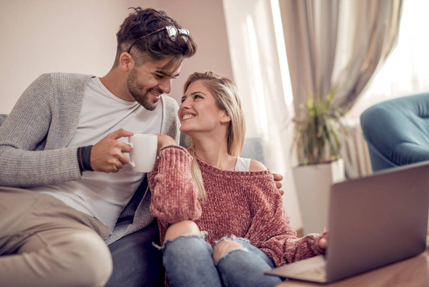Couple sitting on sofa ,drink coffee and using laptop at home. - Photo, Image