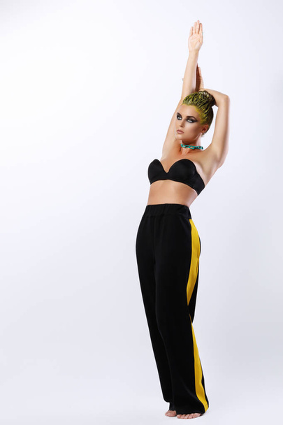Stylish young woman with yellow hair in pants with stripe posing on white background - Zdjęcie, obraz
