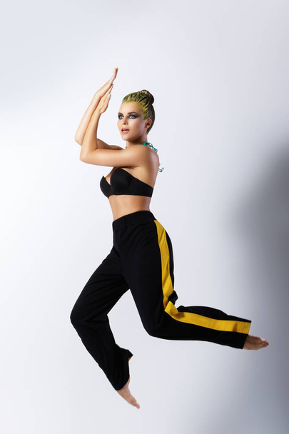 Stylish woman with yellow hair dancing in jump - Фото, зображення