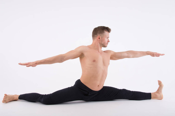 Young handsome man and exercises. Training and relaxation. Healthy lifestyle. Splits - Photo, image