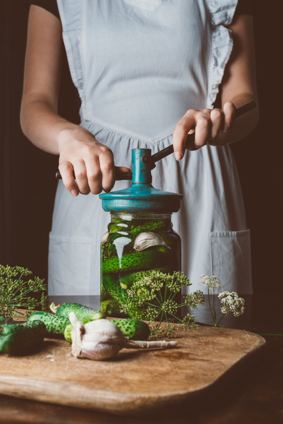 cropped image of woman preparing preserved cucumbers at kitchen table - Photo, Image