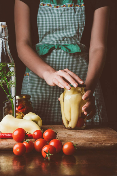 cropped image of woman preparing preserved bell peppers at kitchen - Foto, immagini