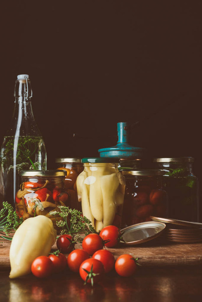 glass jars with preserved vegetables and fresh vegetables on table - Photo, image