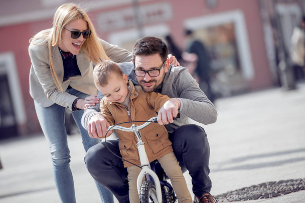 Criança menino andando em sua primeira bicicleta com mãe e pai
. - Foto, Imagem