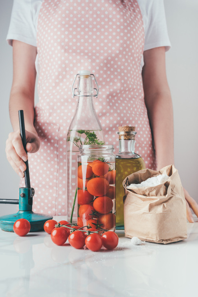 oříznutý obraz ženy připravuje konzervovaná rajčata v kuchyni - Fotografie, Obrázek