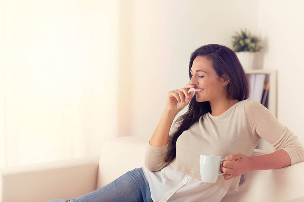 Portrait of cheerful woman with a coffe mug on a couch at home - Photo, Image