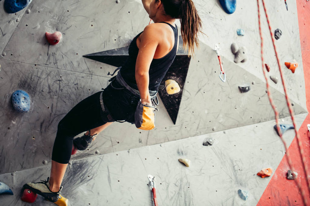 Climber young woman climbing on practical wall indoor, bouldering, recreation, sport - Фото, зображення