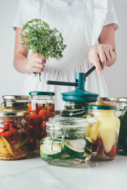 обрізане зображення жінки, що готує консервовані овочі в скляних банках на кухні
 - Фото, зображення