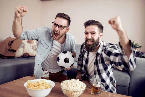 友情、スポーツ、人々、エンターテイメント コンセプト - 自宅テレビでサッカーを見ている男性の幸せの友人. - 写真・画像