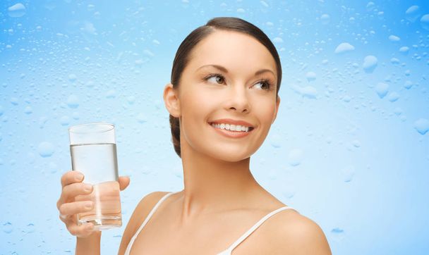 woman with glass of water over wet blue background - Foto, afbeelding