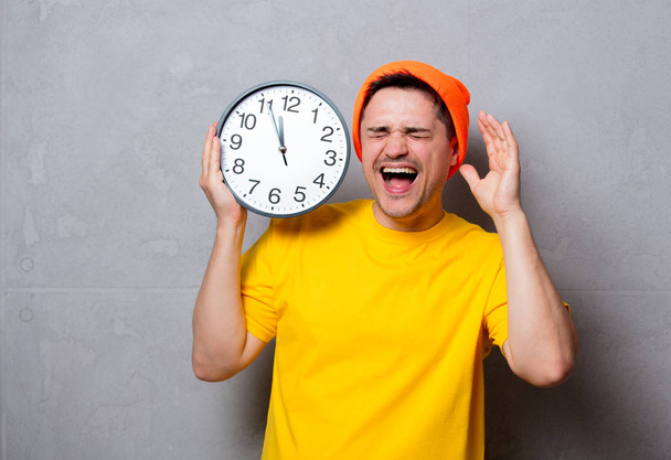 man in yellow t-shirt and hat with big clock - Photo, Image