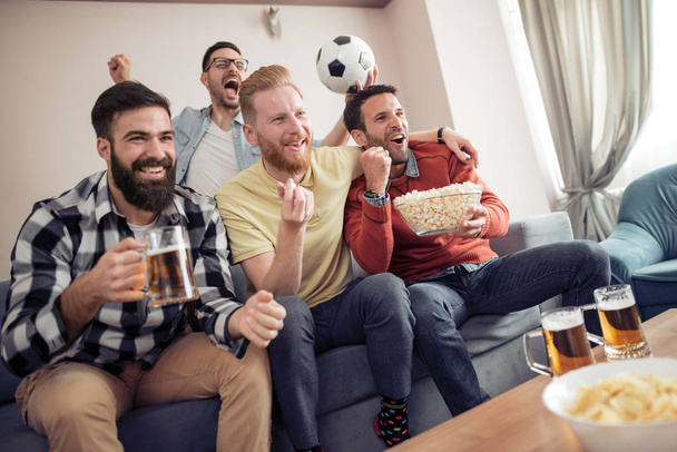 Groupe d'amis regardant le match de football à la télévision et célébrant le but
. - Photo, image