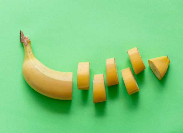 Yellow cut banana isolated on green background - Photo, Image