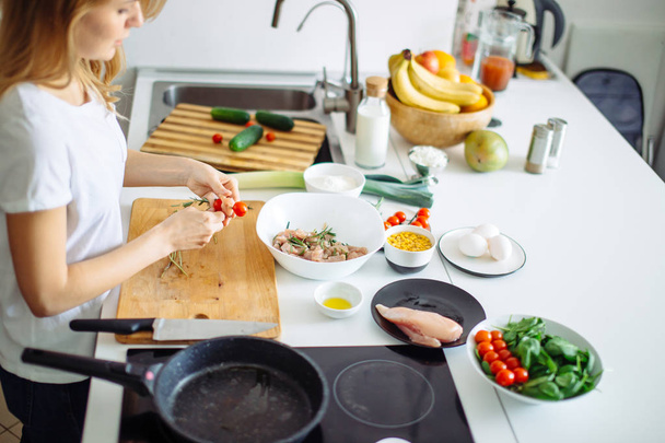 Woman making kebabs from meat and vegetable on chopping board in kitchen - Foto, afbeelding