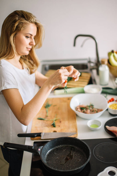 Woman making kebabs from meat and vegetable on chopping board in kitchen - Foto, Bild