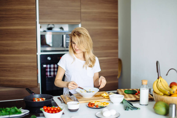 Kobieta mieszanie pyszne składniki sałatki superfood z drewnianymi łyżeczkami w kuchni - Zdjęcie, obraz
