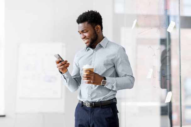 businessman with smartphone and coffee at office - Foto, imagen
