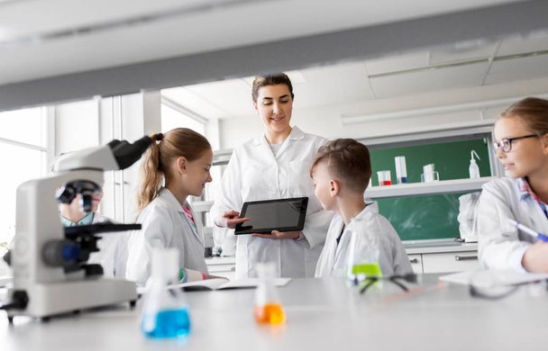 teacher with tablet pc and kids at chemistry class - Photo, image