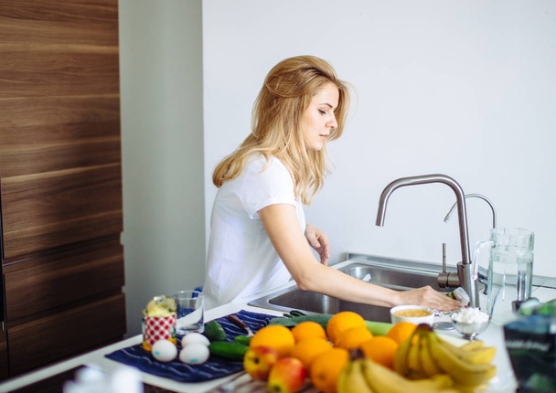 Nuori nainen puhdistaa astiat keittiössä - Valokuva, kuva