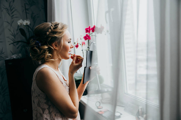 young  beautiful  bride applying lipstick  indoors - Fotografie, Obrázek