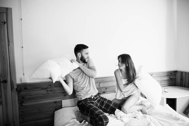 young  couple  in the morning in bed having pillow fight  - Foto, afbeelding