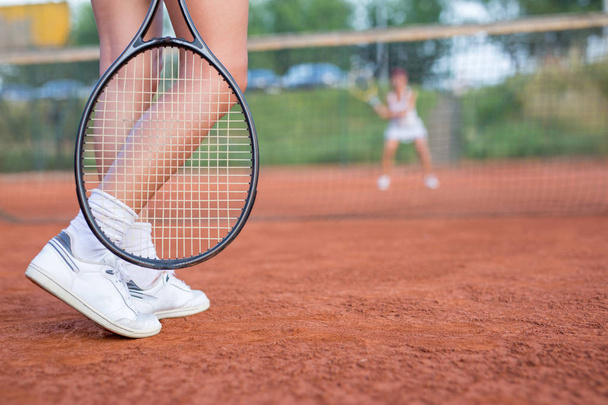 Pernas femininas em um campo de tênis com raquete fora
 - Foto, Imagem