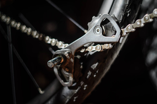 Rear Bicycle Derailleur Fell Apart in Half. Bicycle Rear Derailleur Foot is Detached from the Body. Unexpected Bike Failure. The Torn Off Derailleur Foot Hangs on Chain - Foto, Imagen