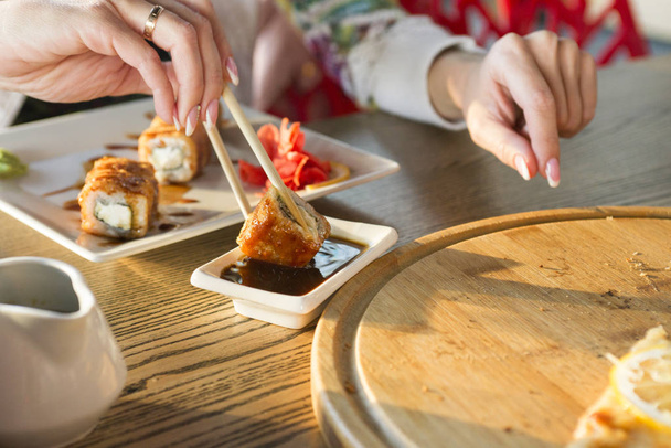 Giovane donna che mangia sushi roll in un ristorante
 - Foto, immagini