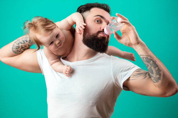 Father holding and taking care of little infant baby, feeding from bottle. - 写真・画像