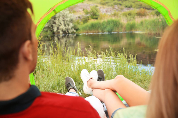 Young couple resting in camping tent near pond, view from inside - Fotoğraf, Görsel
