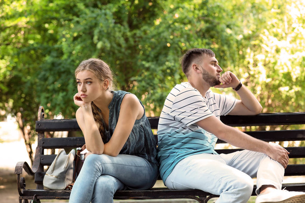 Young couple arguing while sitting on bench in park. Problems in relationship - Foto, Imagen