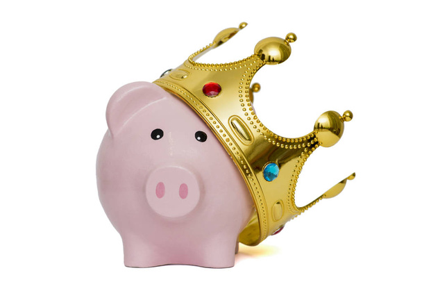 Financiële winnaar of koning van geld besparingen concept, roze spaarvarken draagt een gouden kroon geplaatst op een witte achtergrond, beste toekomstige investeringen - Foto, afbeelding