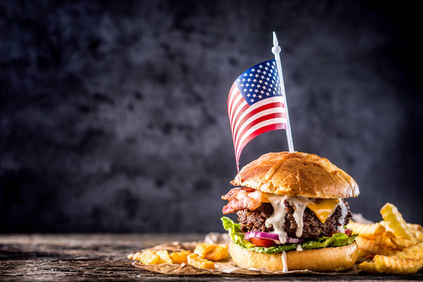 Close-up home made beef burger with american flag and fries on wooden table. - Фото, изображение