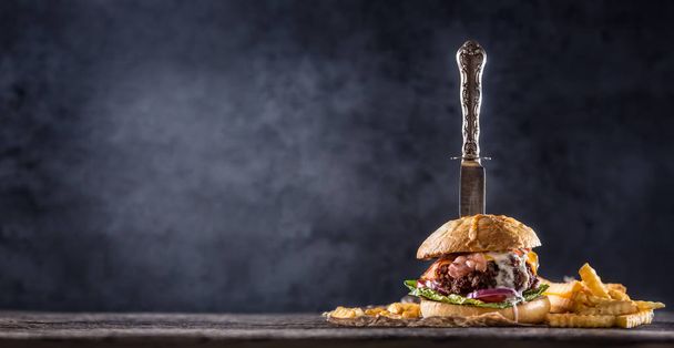 Close-up home made beef burger with knife and fries on wooden table. - Foto, immagini