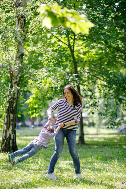 Mother and daughter having fun and playing together in the public park. - Photo, Image