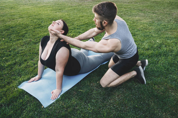 Obese woman doing yoga with personal trainer - Foto, Bild