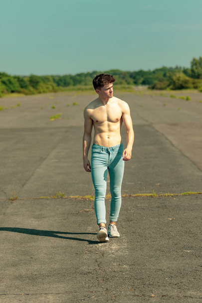 Young adult male walking forward shirtless on a warm summer's day - Fotó, kép